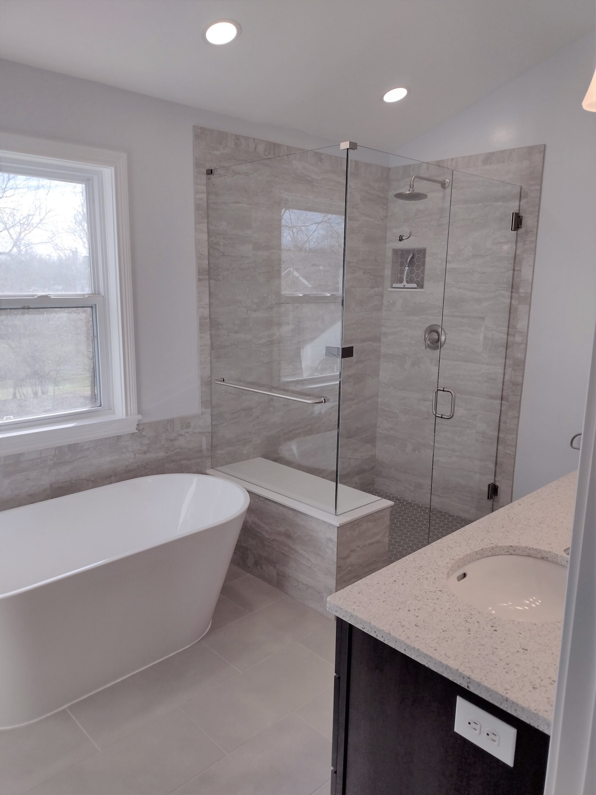 An image depicting a bathroom with a vanity, tub, and standing shower.