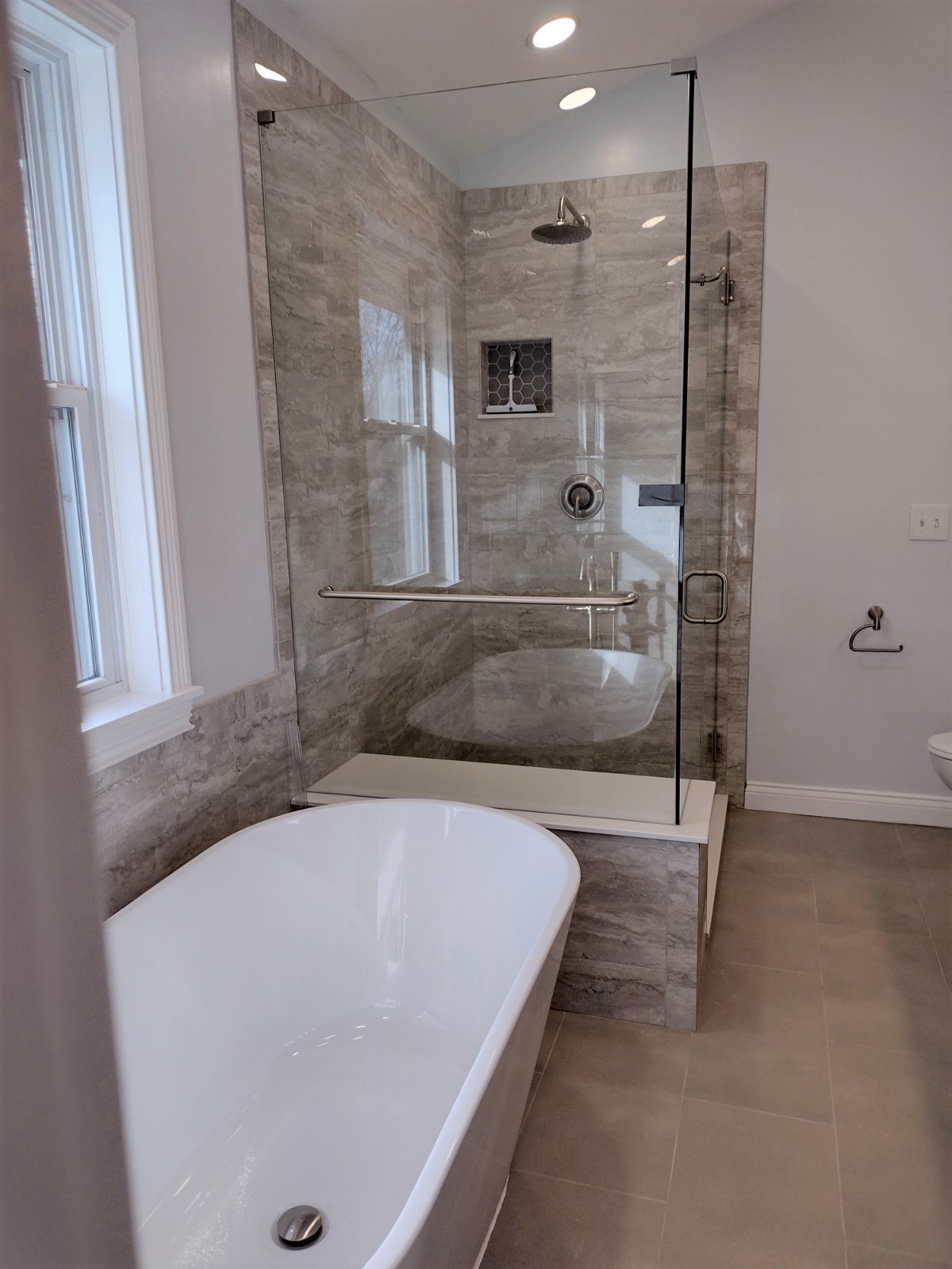 A bathroom with a white tub and standing shower.